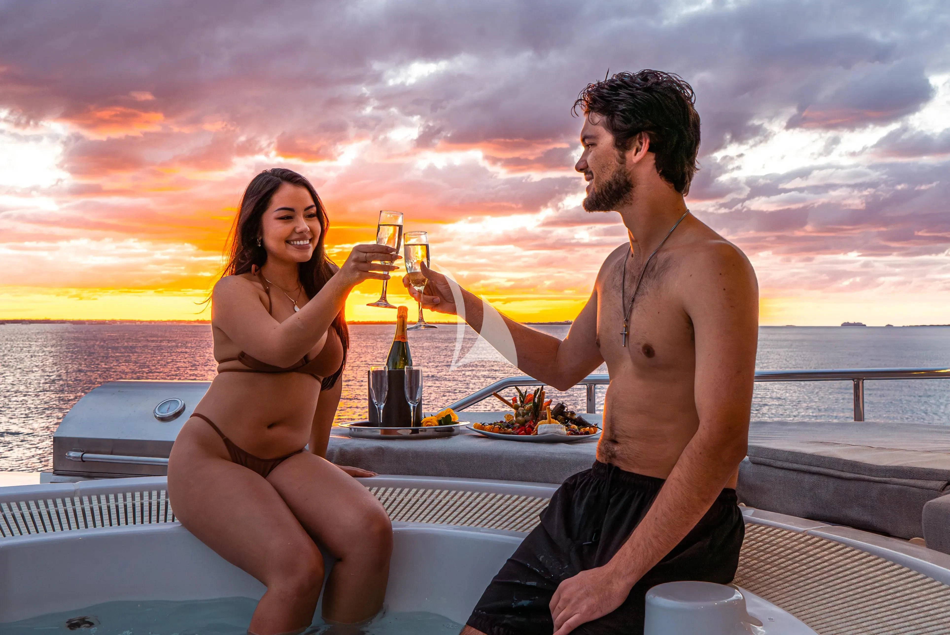 a man and woman sitting on a boat holding glasses of beer aboard BRANDI WINE Yacht for Charter