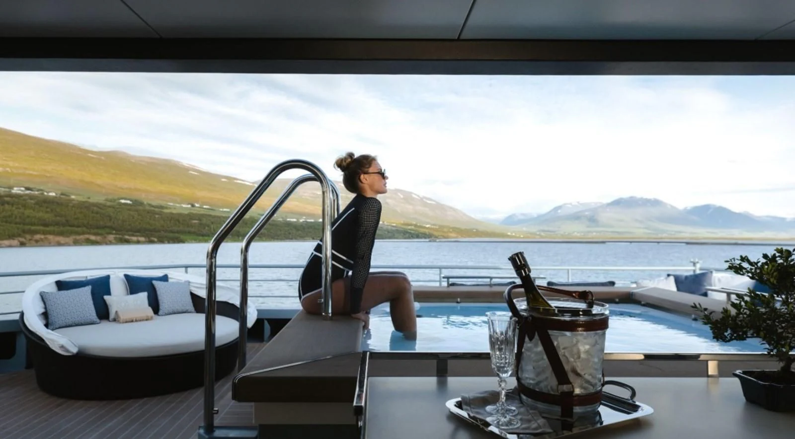 a person sitting on a chair on a deck overlooking a body of water aboard Q Yacht for Sale
