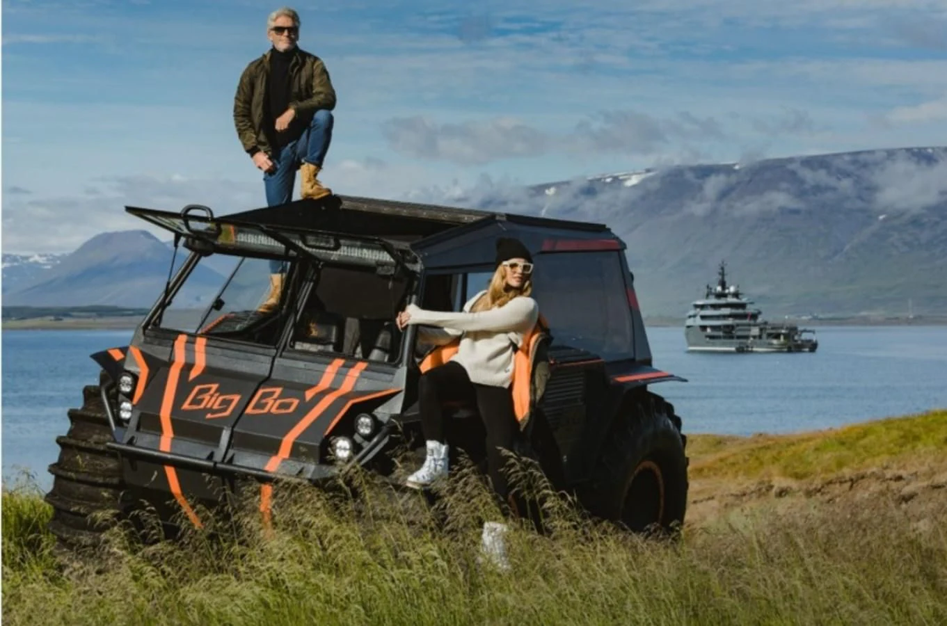 a man and woman posing for a picture next to a vehicle aboard Q Yacht for Sale