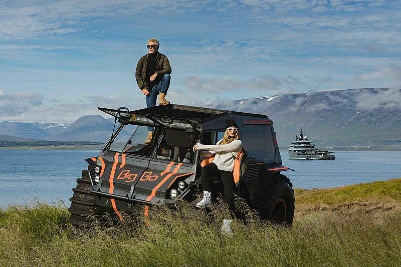 a couple of men sitting on a tractor in a field with a boat in the background aboard Q Yacht for Sale