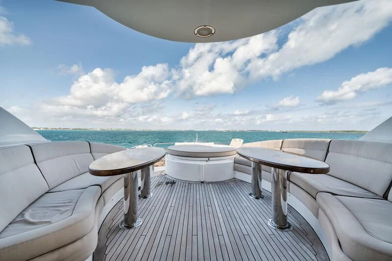 a table and chairs on a deck overlooking a beach aboard LADY KRISTINA Yacht for Sale