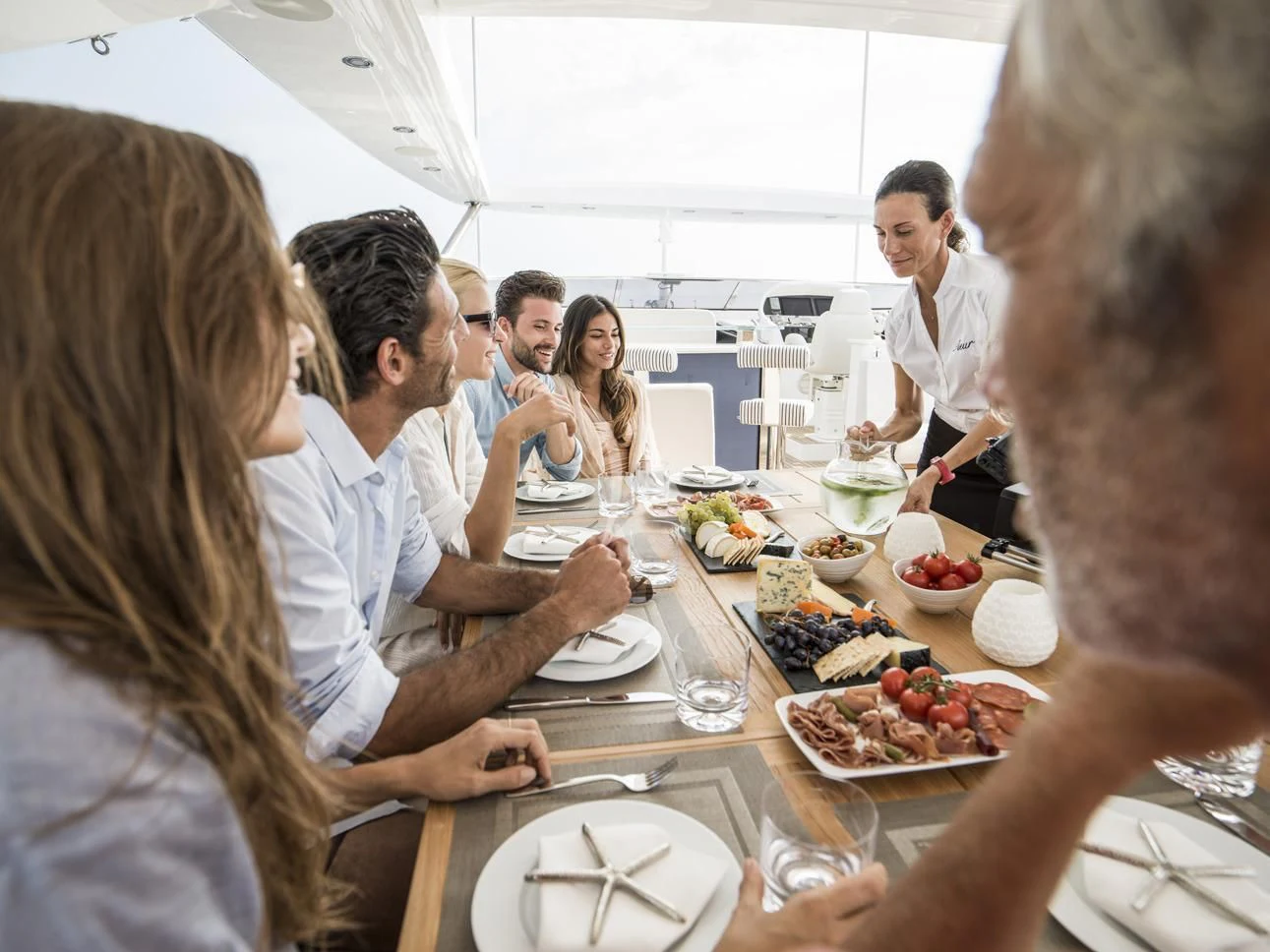 a group of people sitting around a table eating food aboard FLEUR Yacht for Charter