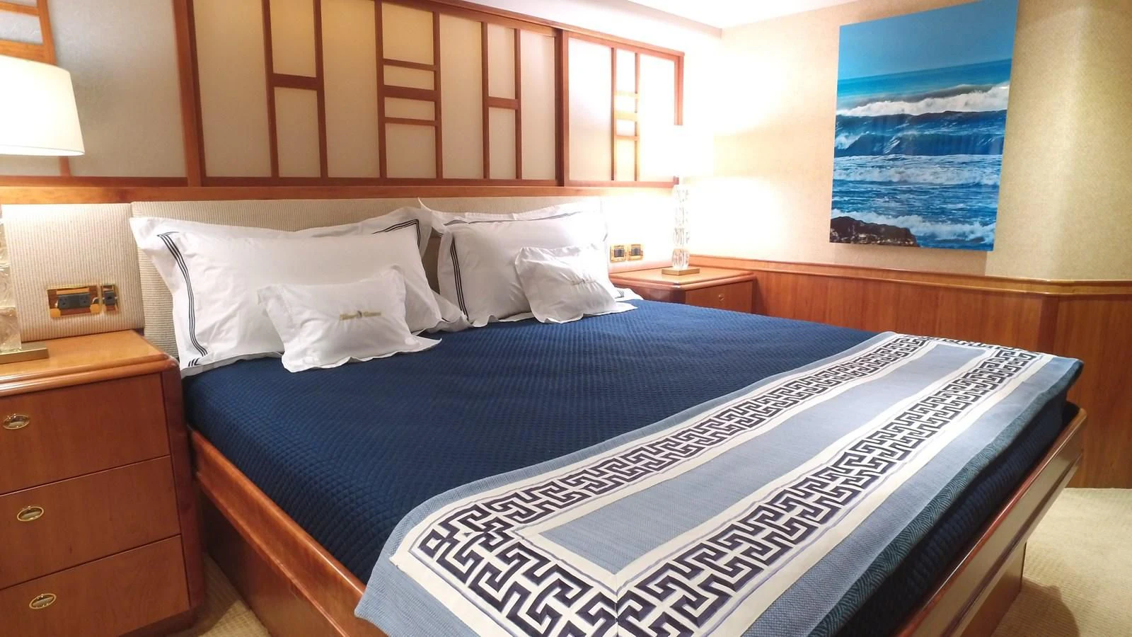 a bed with a blue and white comforter and a blue painting on the wall aboard ELYSIAN Yacht for Sale