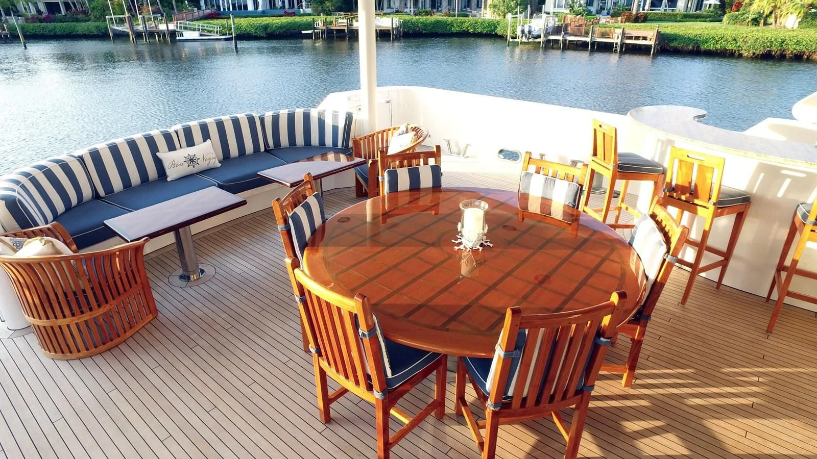 a wooden table and chairs on a deck by a body of water aboard ELYSIAN Yacht for Sale