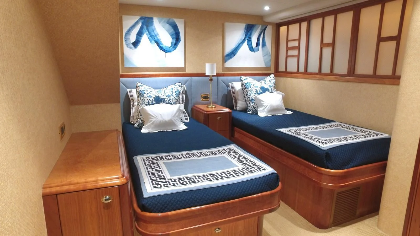 a bed with a blue bedspread and a wooden cabinet aboard ELYSIAN Yacht for Sale