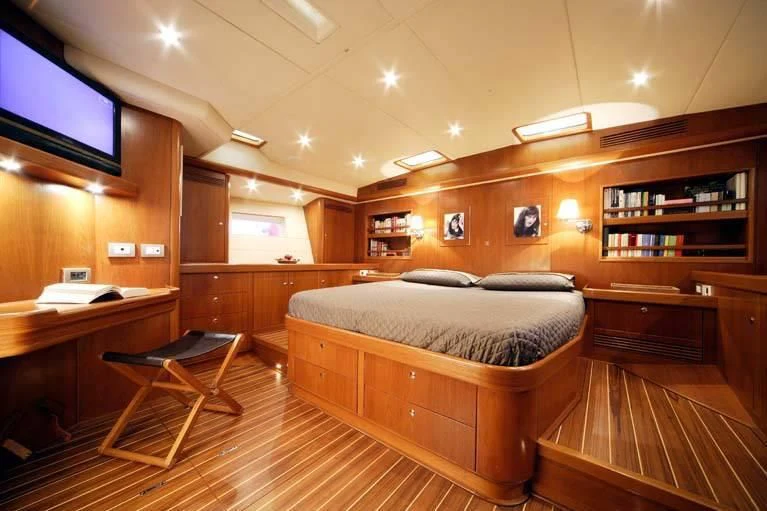 a bedroom with a bed and desk aboard DHARMA Yacht for Sale
