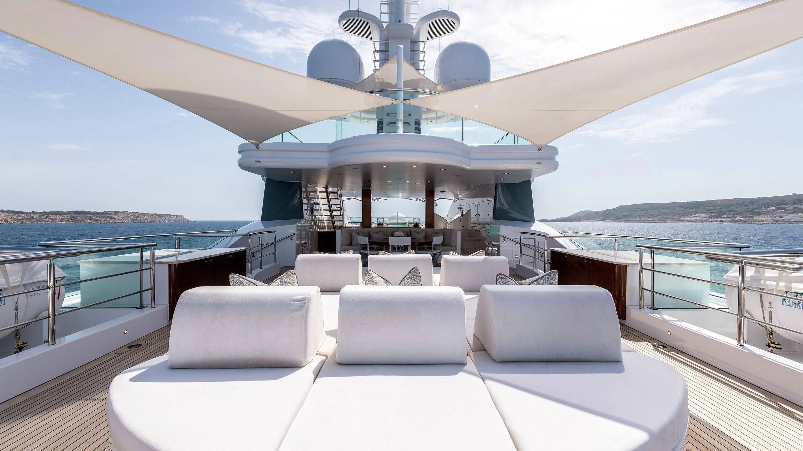 a large white lounge chair on a deck overlooking a body of water aboard TALISMAN C Yacht for Charter