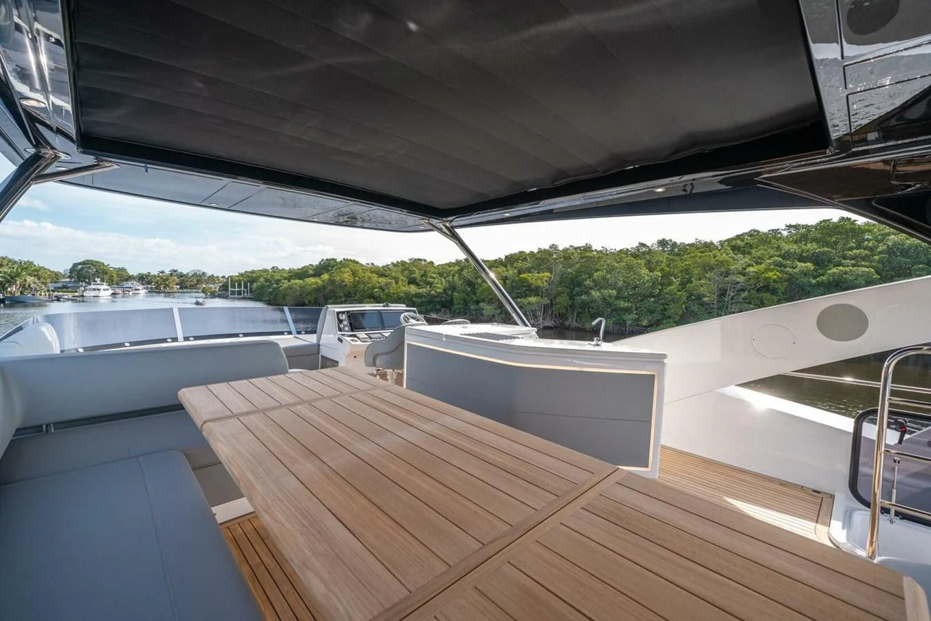 a deck with a wood table and a large window with trees and grass aboard 76 YACHT Yacht for Sale