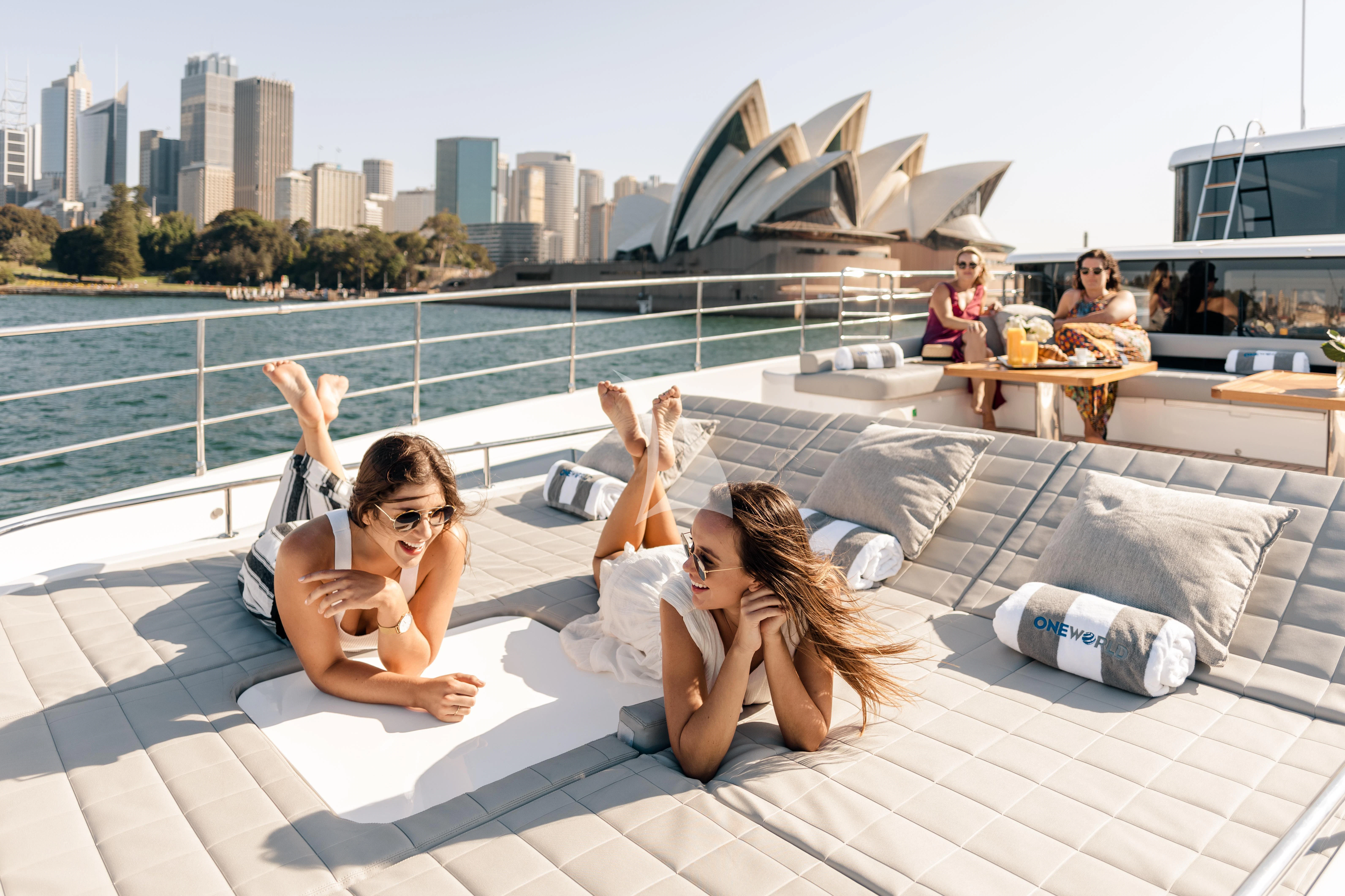 a couple of women sitting on a rooftop with their feet up aboard ONEWORLD Yacht for Sale