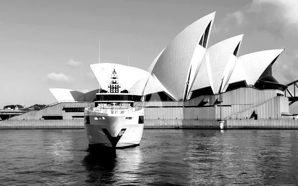 a group of sailboats on water with Sydney Opera House in the background aboard ONEWORLD Yacht for Sale