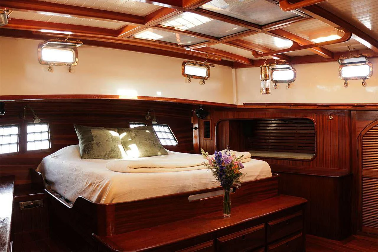 a bed with a table and a vase of flowers on it aboard TREE OF LIFE Yacht for Sale
