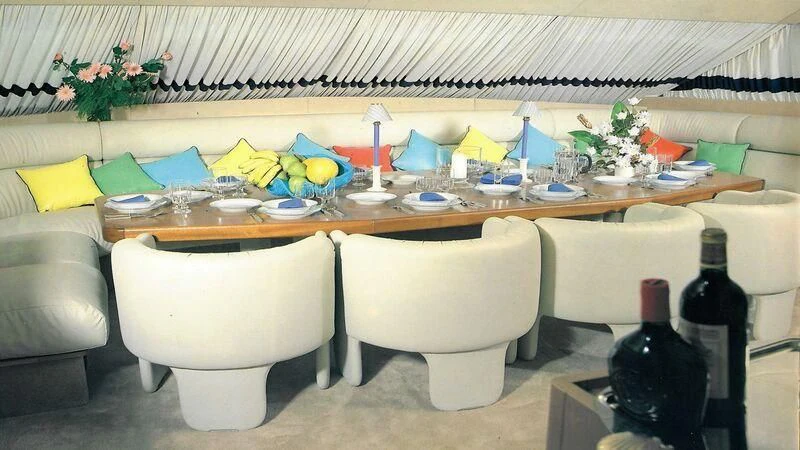 a white chair next to a table with food and bottles on it aboard SOMETHING WILD Yacht for Sale