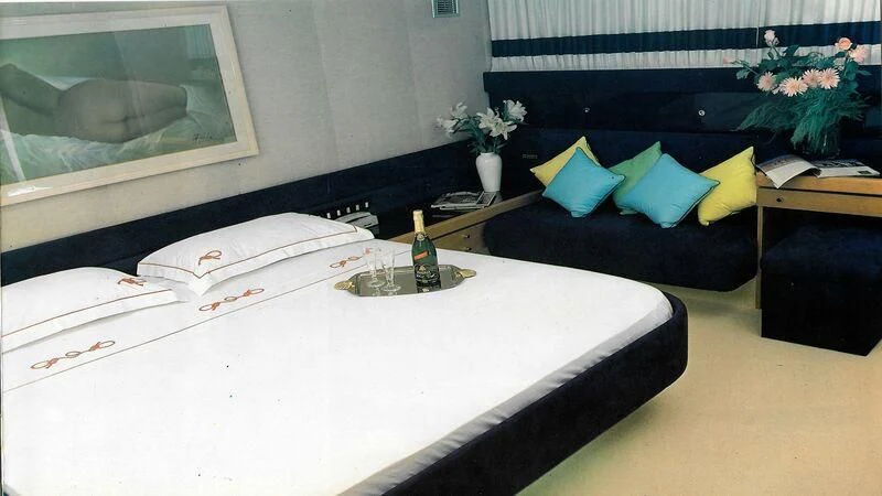 a bed with a white sheet and blue pillows aboard SOMETHING WILD Yacht for Sale