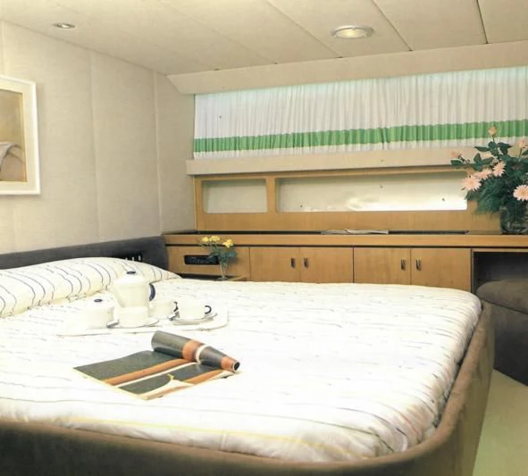 a bed with a white sheet and a green wall behind it aboard SOMETHING WILD Yacht for Sale