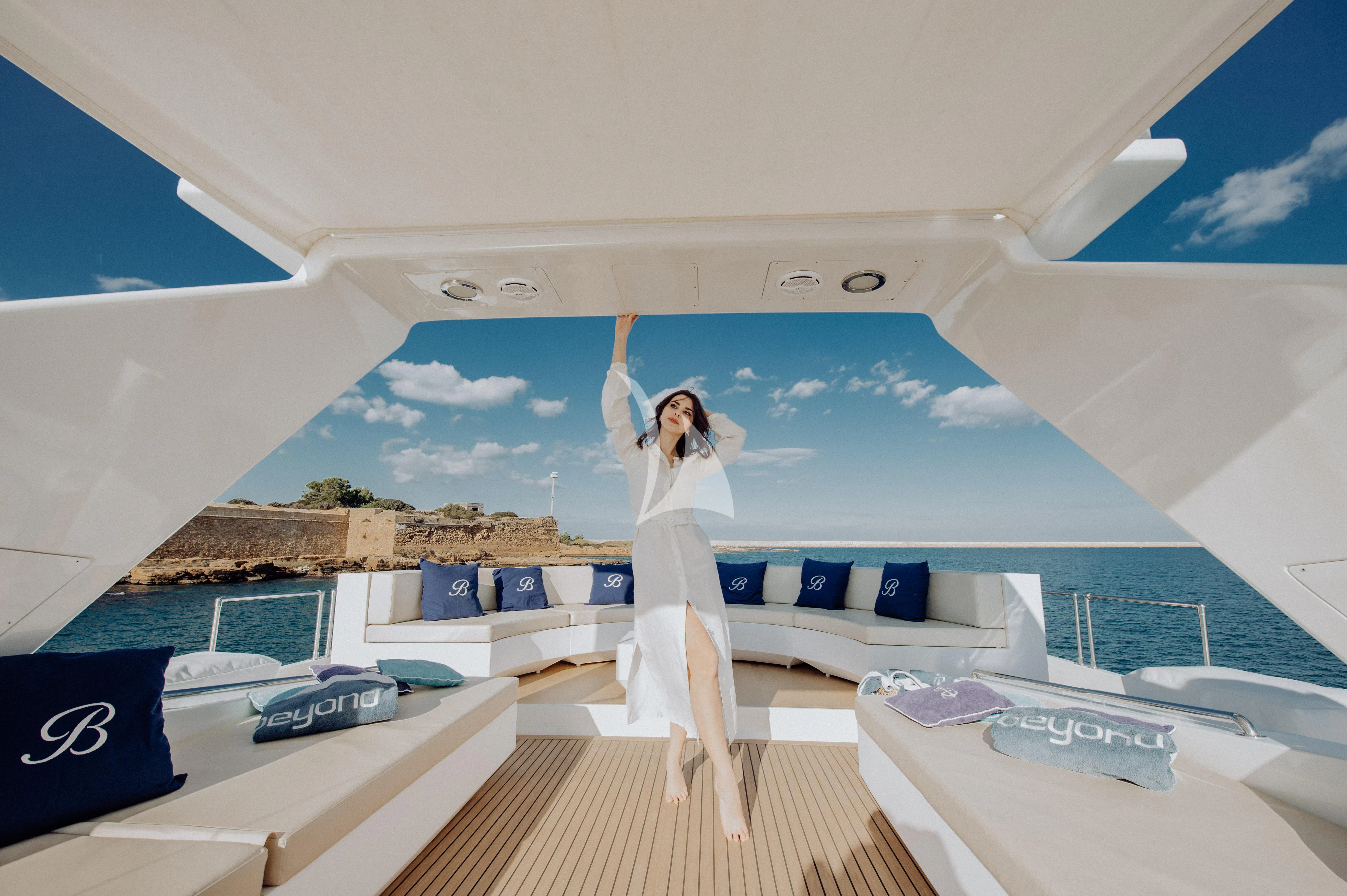 a person in a white dress on a lounge chair in a room with a large white window and aboard BEYOND Yacht for Charter