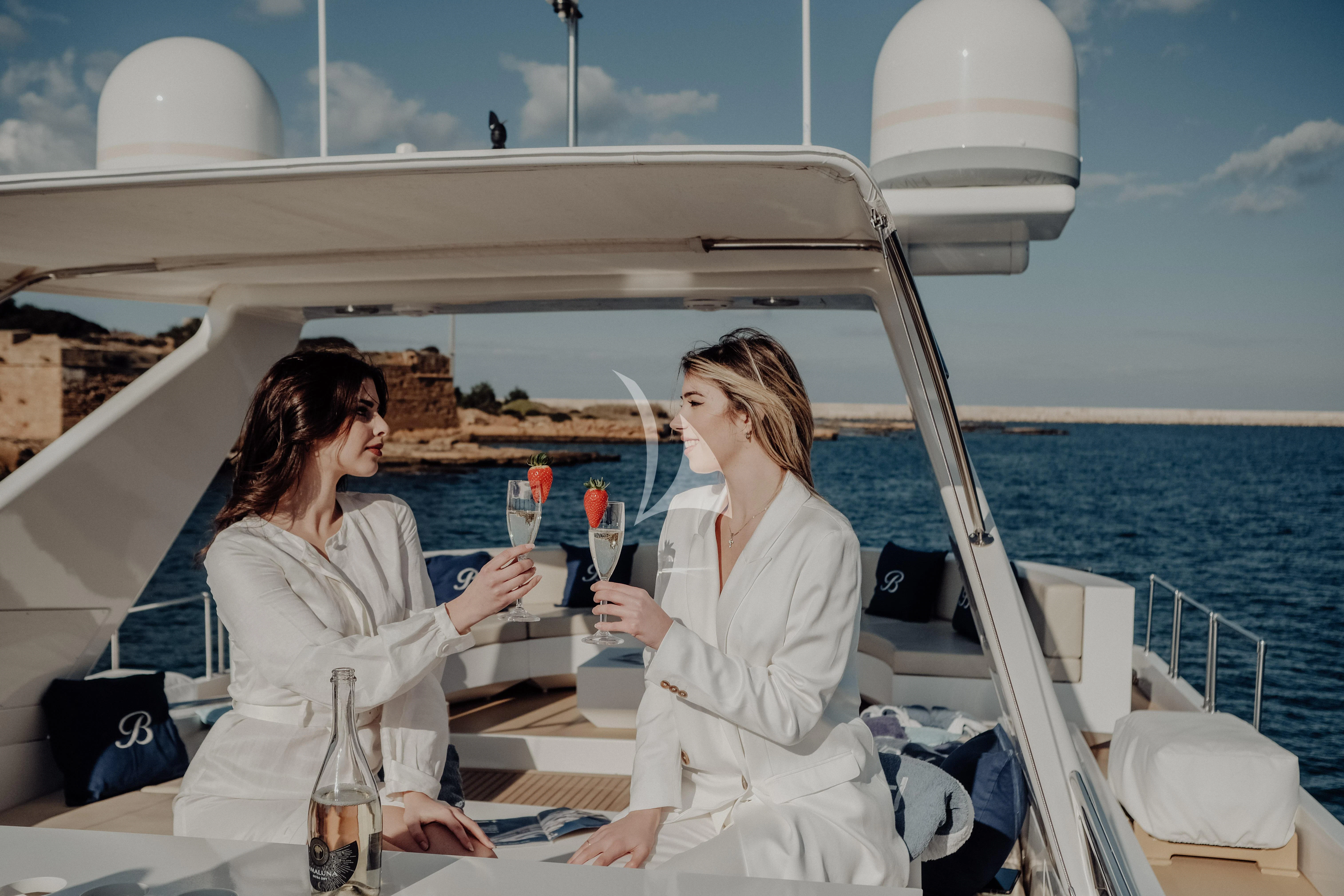 a couple of women sitting on a boat drinking wine aboard BEYOND Yacht for Charter