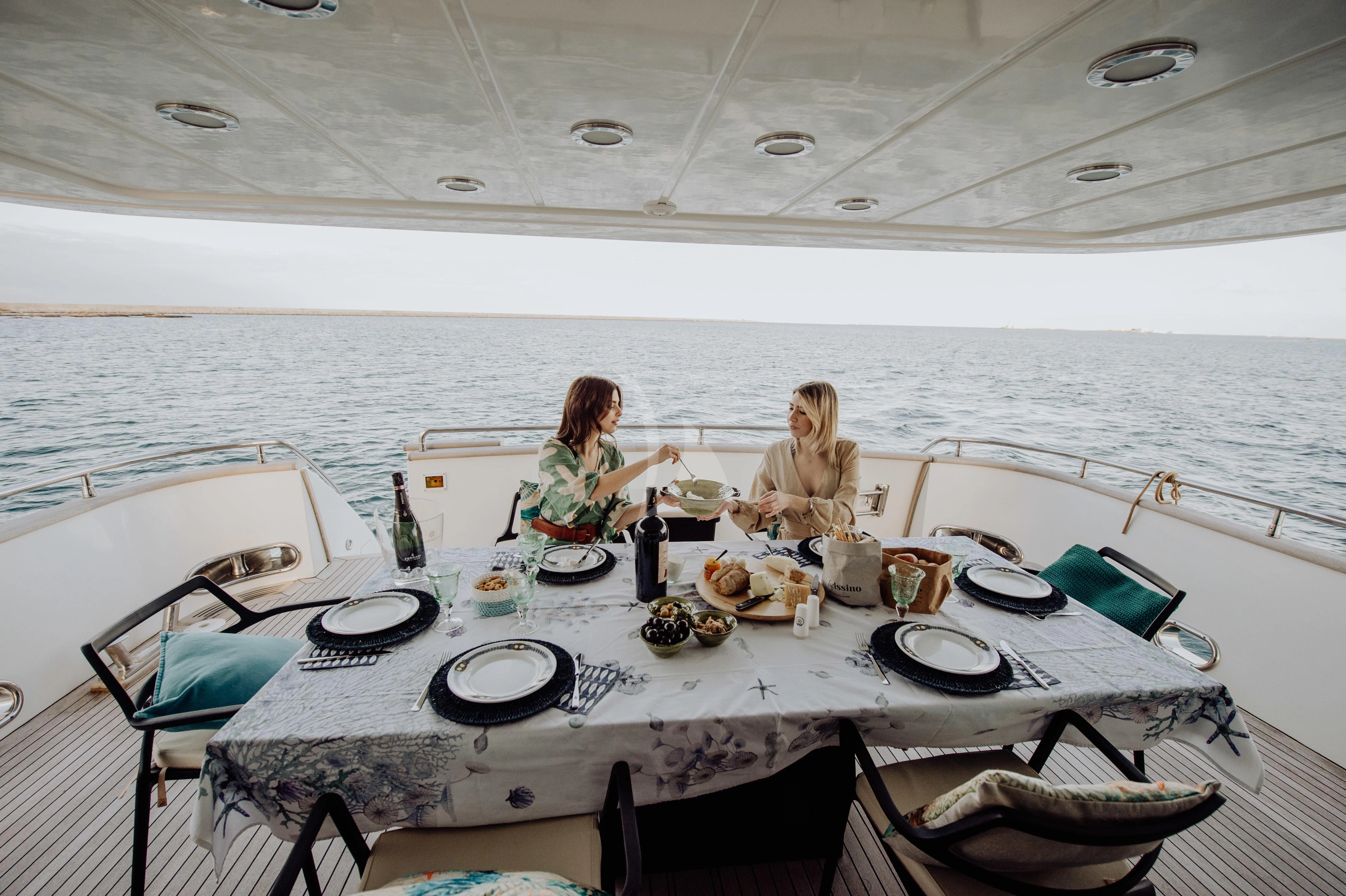 a couple of women sitting on a boat with a table full of food aboard BEYOND Yacht for Charter