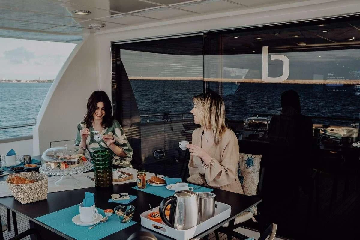 a couple of women sitting at a table with food and drinks aboard BEYOND Yacht for Charter