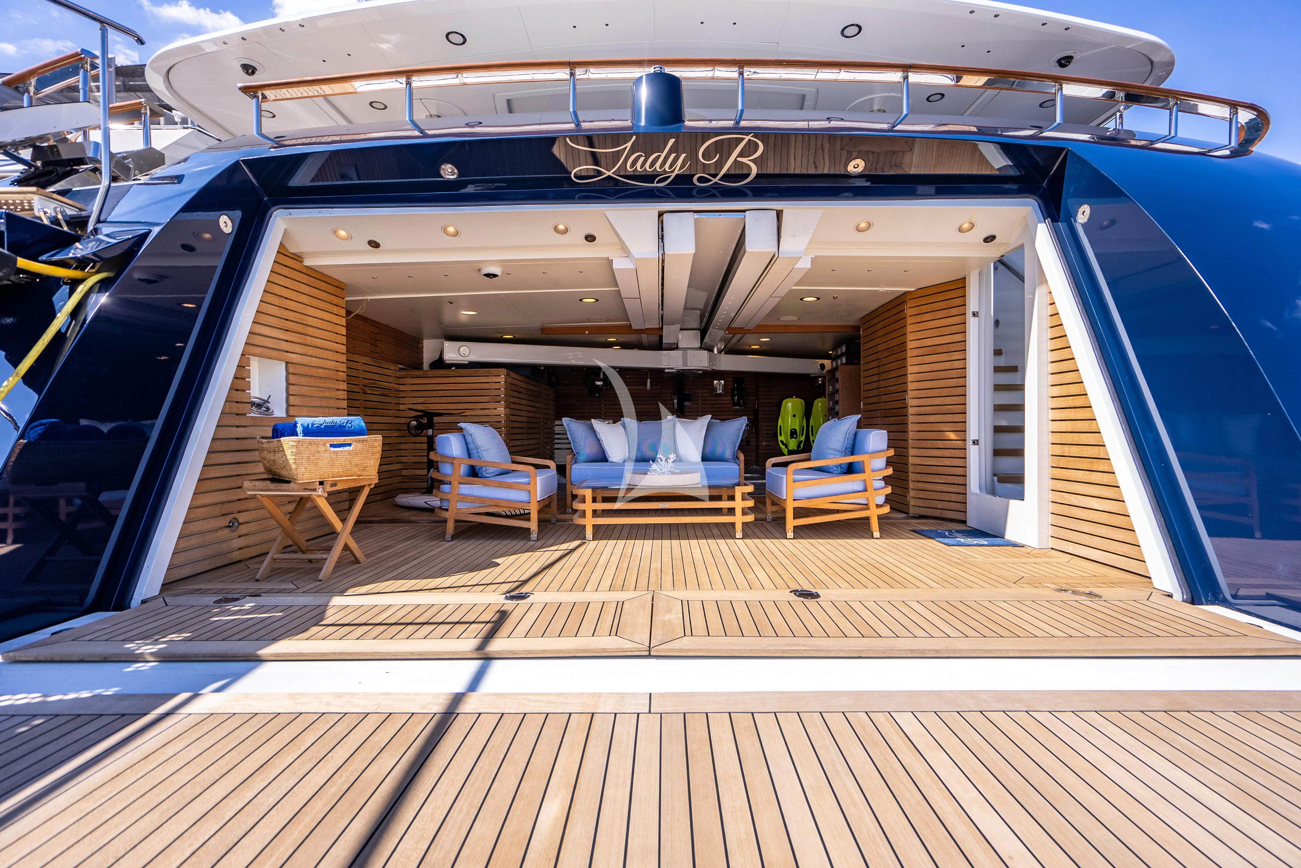 a wooden deck with chairs and a large ship in the background aboard LADY B Yacht for Charter