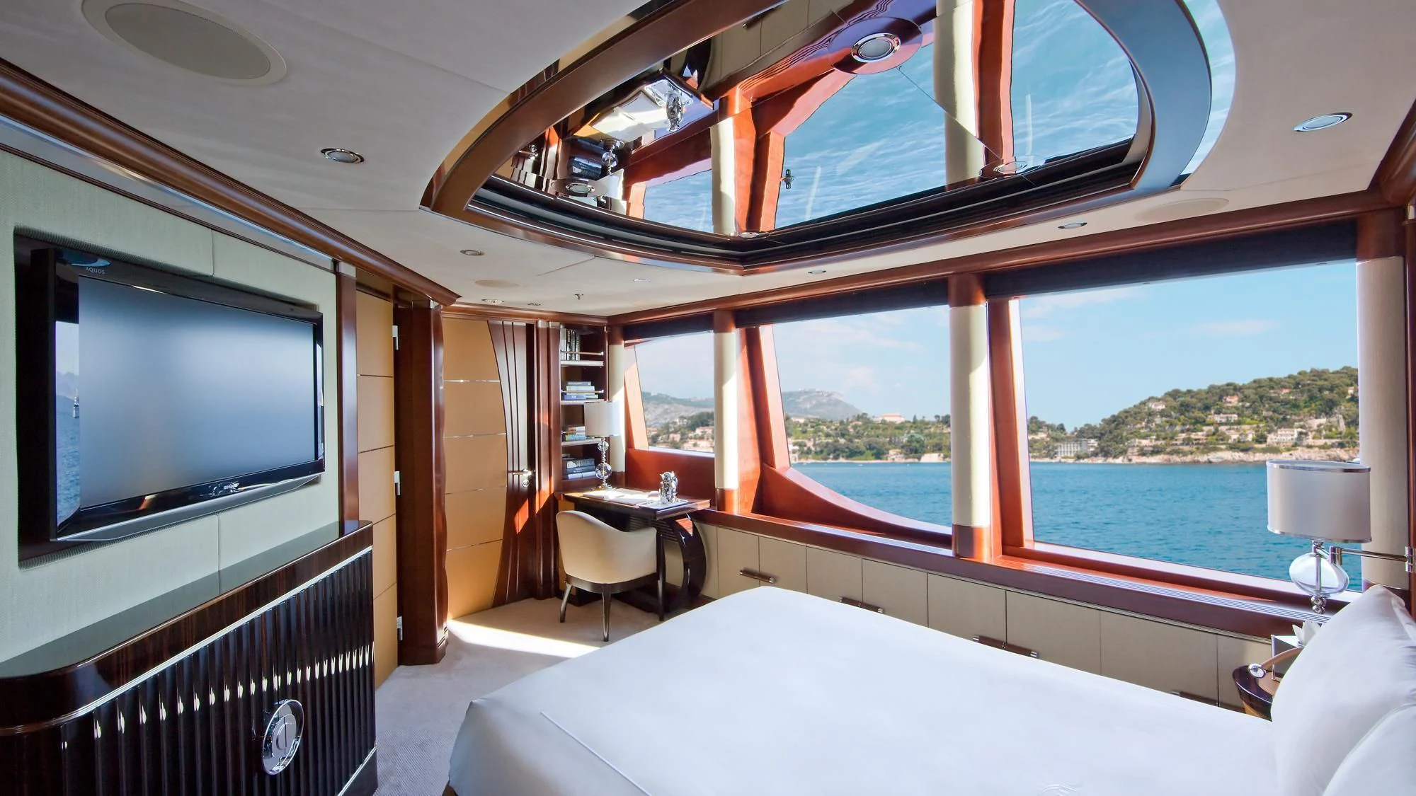 a room with a large window and a bed and a television aboard LADY B Yacht for Charter