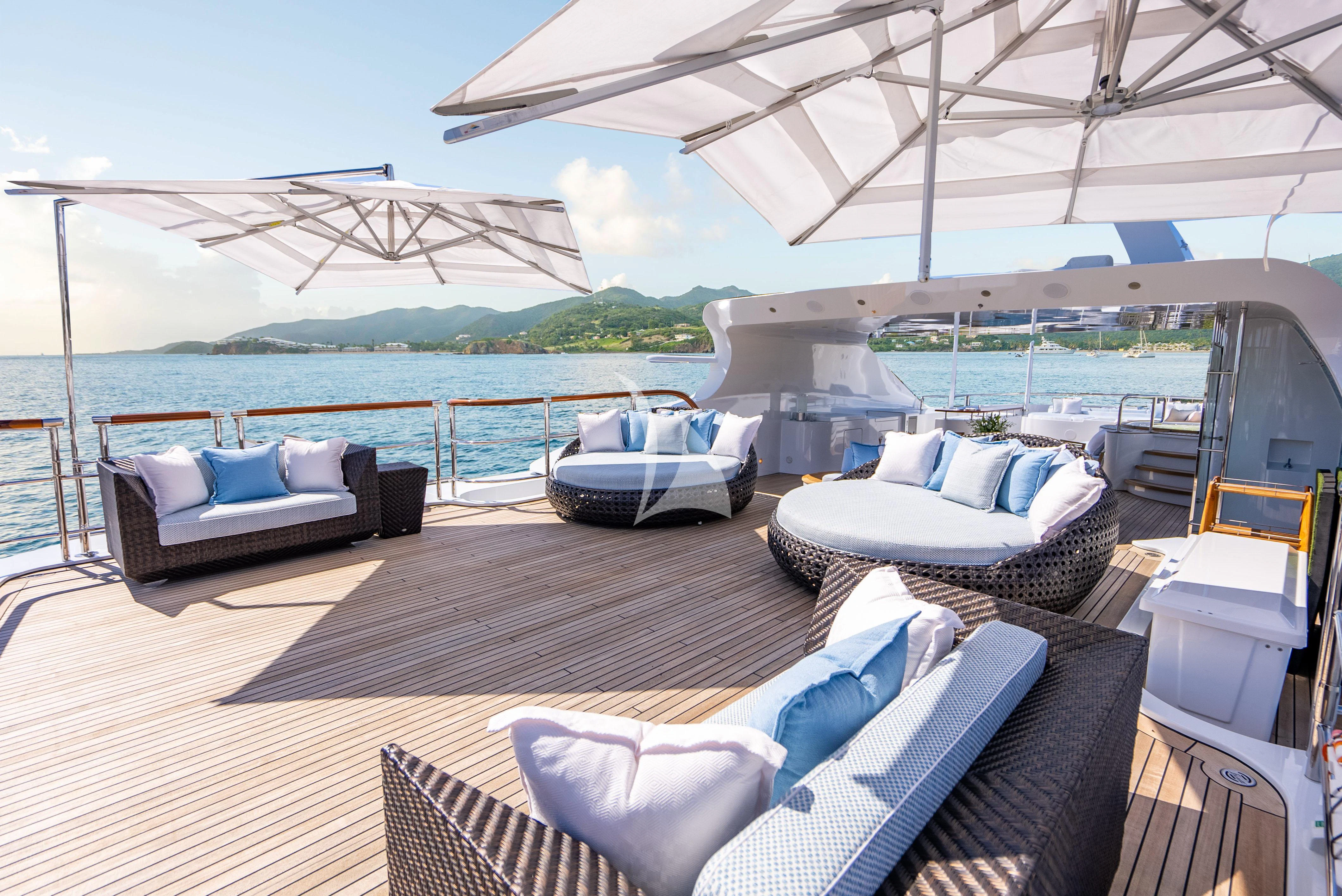 a large lounge area with a large body of water and a large building in the background aboard LADY B Yacht for Charter