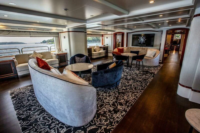 a living room with a large blue couch and a wood floor aboard THE STAR Yacht for Sale
