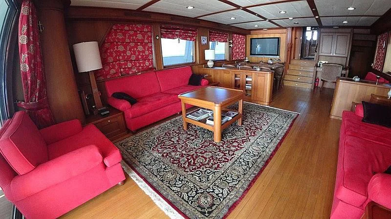 a living room with red couches and a coffee table aboard KUYIS Yacht for Sale