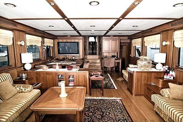 a living room with a large wood table and a large television aboard KUYIS Yacht for Sale