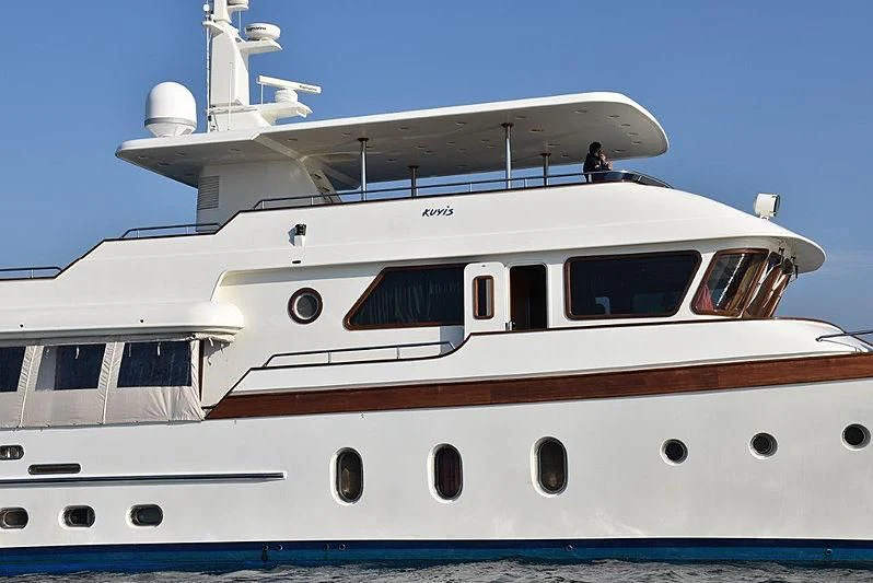 a white yacht with a person on the deck aboard KUYIS Yacht for Sale
