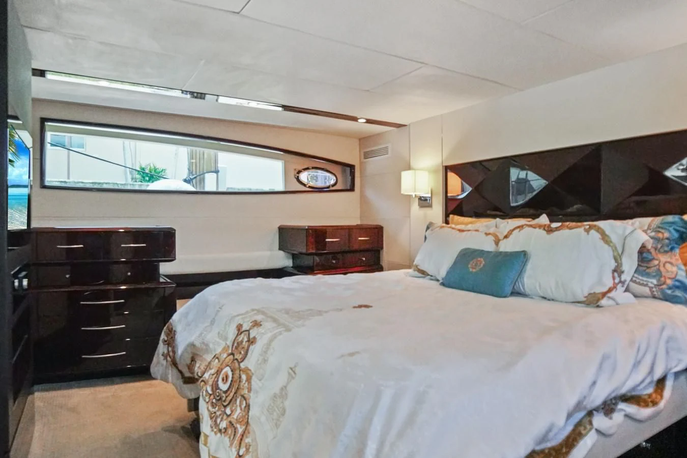a bedroom with a bed and a dresser aboard LAZZARA 68' Yacht for Sale