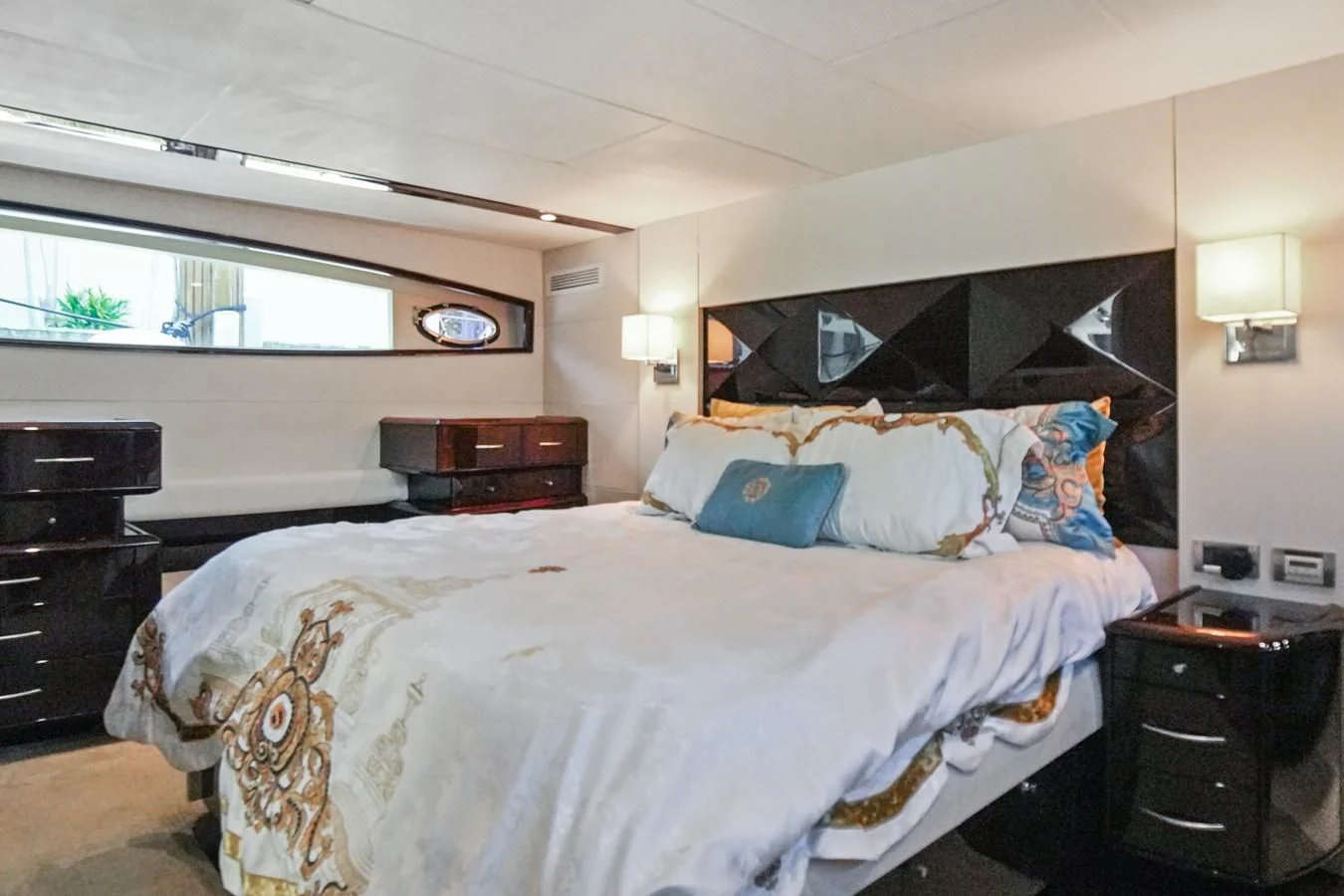 a bedroom with a bed and a dresser aboard LAZZARA 68' Yacht for Sale