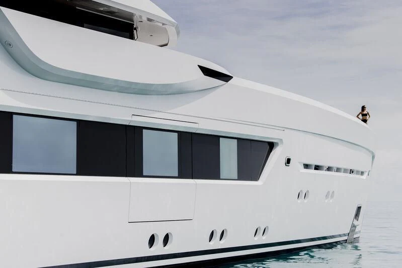 a white yacht with a person standing on the deck aboard ENTOURAGE Yacht for Sale