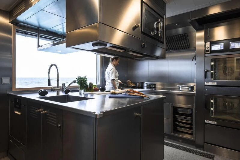 a person cooking in a kitchen aboard ENTOURAGE Yacht for Sale