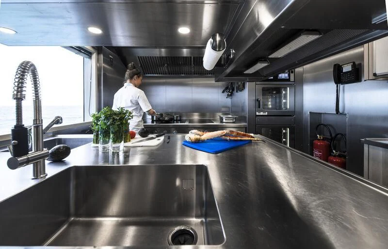 a person cooking in a kitchen aboard ENTOURAGE Yacht for Sale