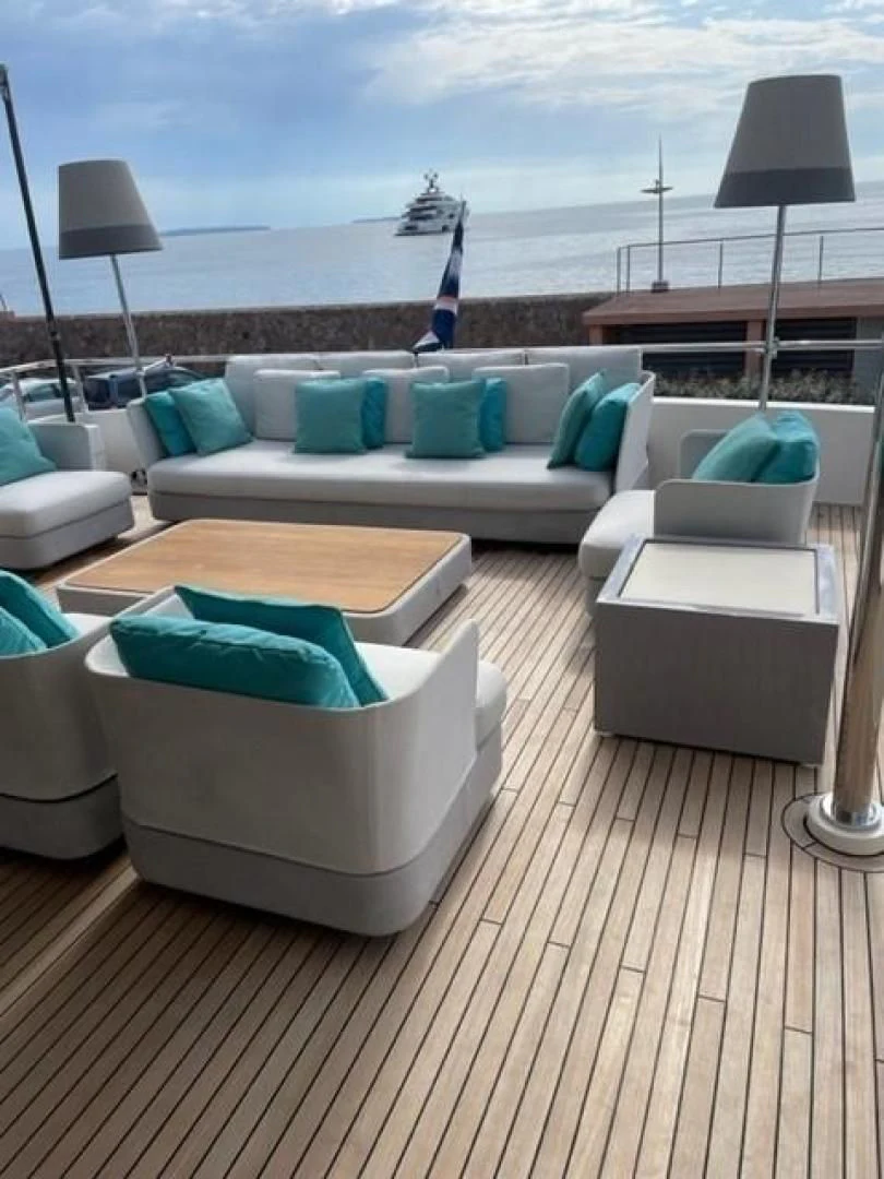 a deck with a couch and a table with chairs and a statue on it aboard ZEN Yacht for Sale