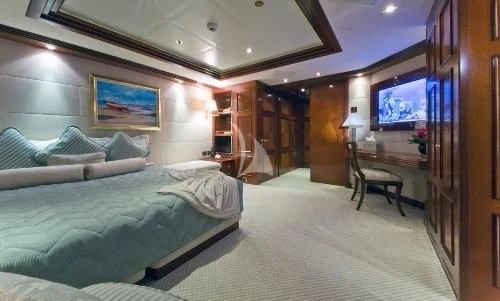 a room with a bed and a television aboard BLUE MOON Yacht for Charter