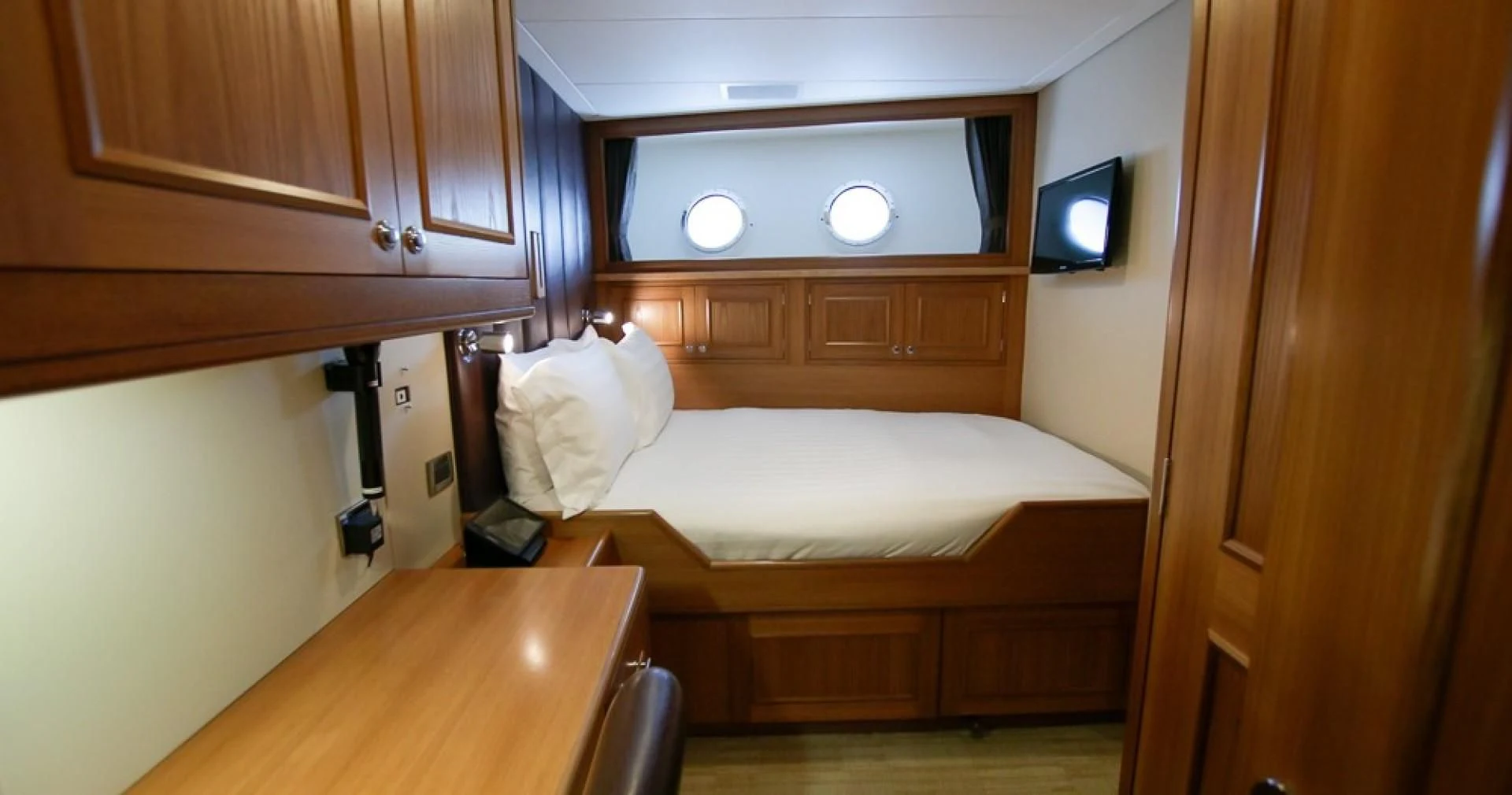 a room with a bed and a television aboard BLUE MOON Yacht for Charter