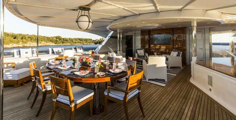 a large room with a table and chairs and a tv aboard BLUE MOON Yacht for Charter