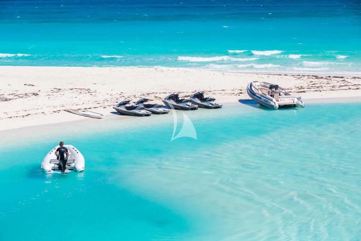 a person standing on a surfboard in the ocean next to a boat aboard LADY ELAINE Yacht for Charter