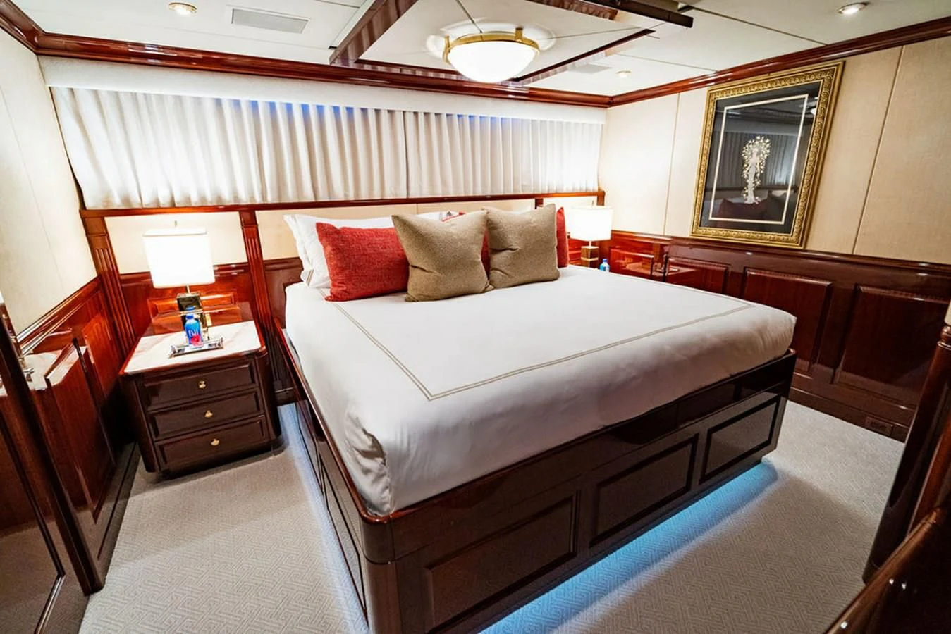 a bed with a white sheet and red pillows aboard LADY ELAINE Yacht for Charter