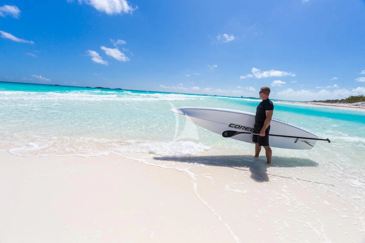 a person carrying a surfboard on a beach aboard LADY ELAINE Yacht for Charter