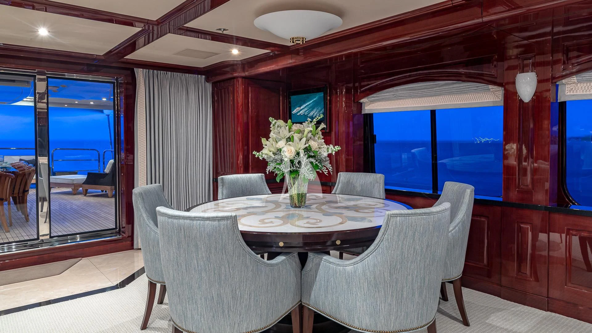 a dining table with chairs and a vase of flowers on it aboard LADY ELAINE Yacht for Charter