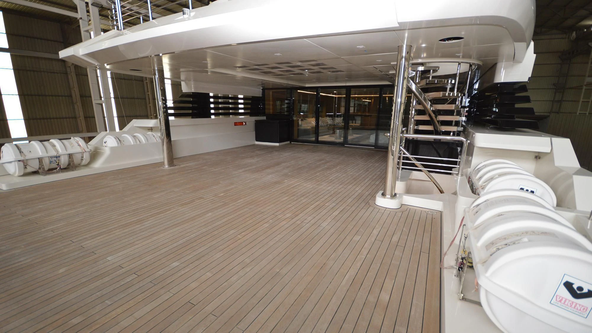 a room with a wood floor and a large white bed and a ladder aboard NAVIS ONE Yacht for Charter