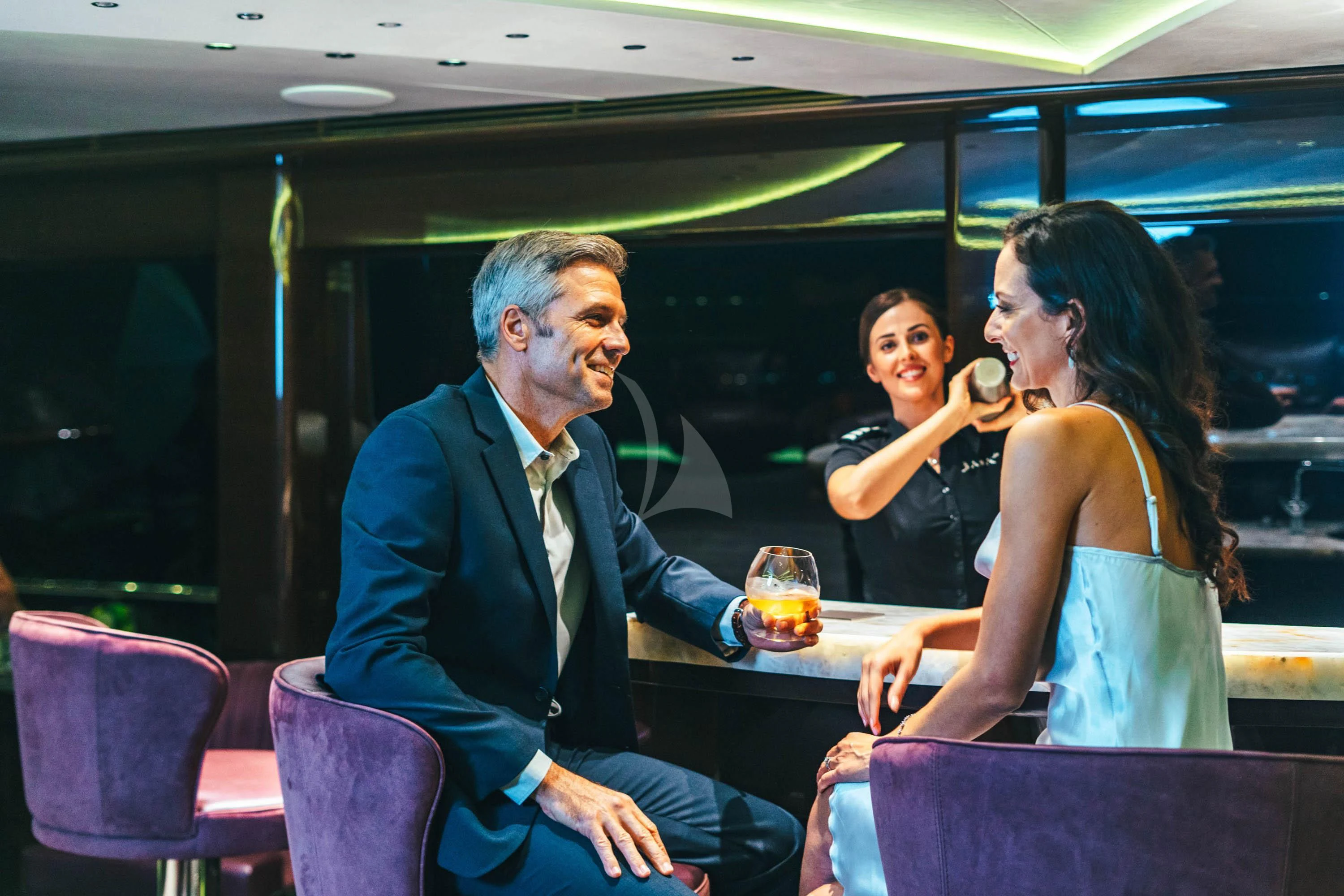a man and woman sitting at a table with drinks aboard BABA'S Yacht for Sale