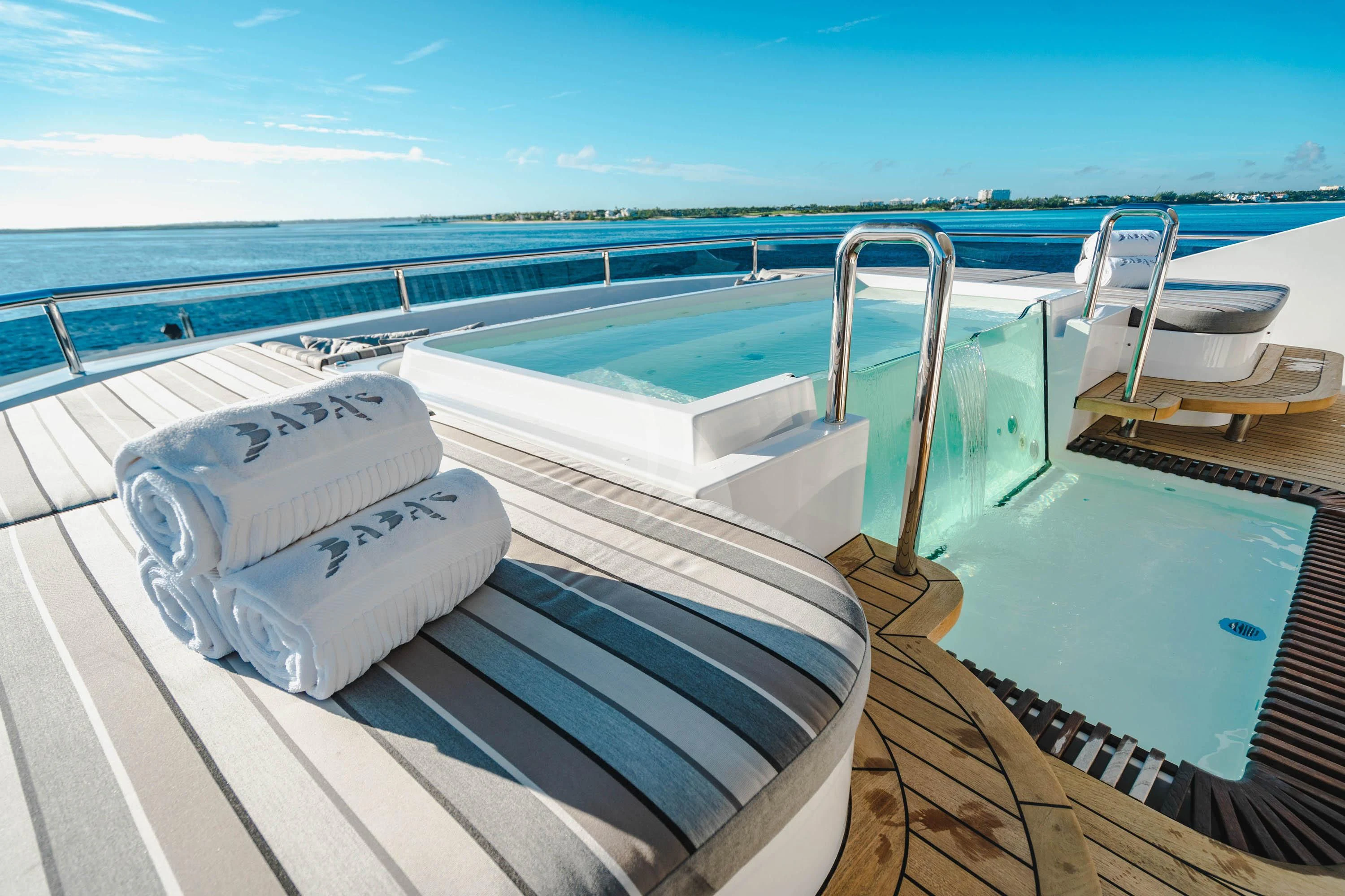 a deck with a pool and a deck with chairs and a large body of water aboard BABA'S Yacht for Sale