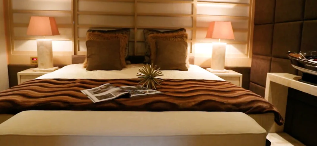 a bed with a lamp and pillows aboard ANNA J Yacht for Sale