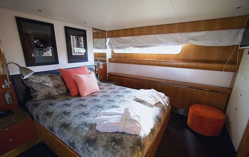 a bed with a brown comforter and pink pillows aboard CURIOSITY Yacht for Sale