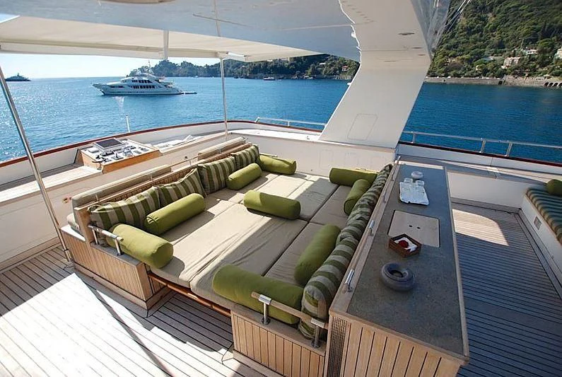 a deck with a pool and boats in the background aboard CURIOSITY Yacht for Sale