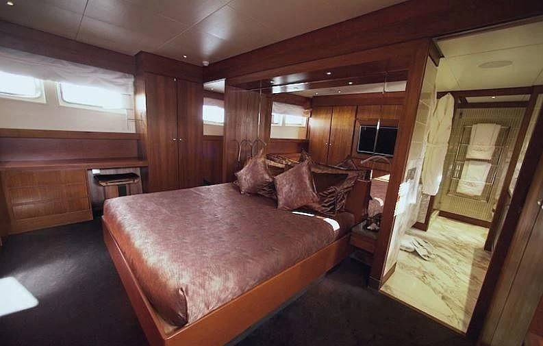 a bedroom with a bed and a wood door aboard CURIOSITY Yacht for Sale