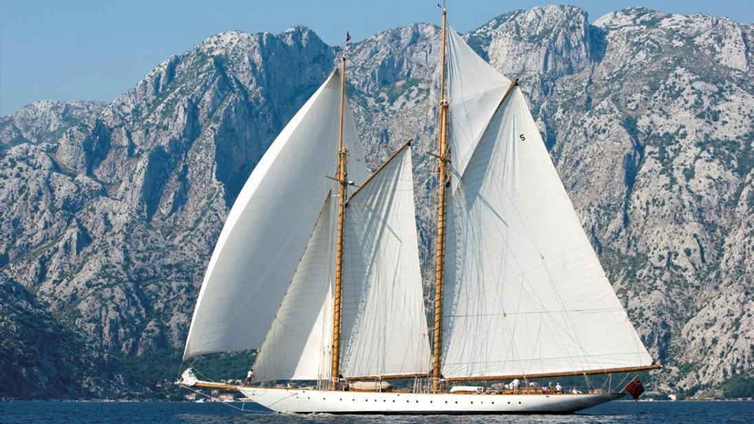a sailboat in front of a mountain aboard ELEONORA E Yacht for Sale